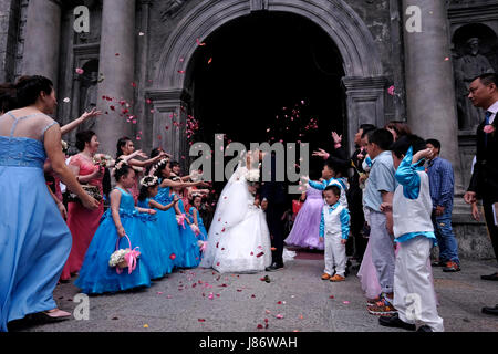 Guests throwing confetti over bride and groom during a Chinese wedding at the Roman Catholic San Agustin Church or Iglesia de la Inmaculada Concepcion de Maria de San Agustin located located inside the historic walled city of Manila referred to as Intramuros in the city of Manila capital of the Philippines Stock Photo