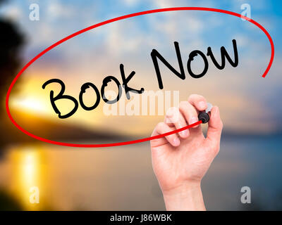 Man Hand writing Book Now with black marker on visual screen. Isolated on nature. Business, technology, internet concept. Stock Photo Stock Photo