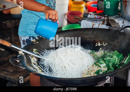 GEORGE TOWN, MALAYSIA - MARCH 23: Woman cooks stir-fried noodles with bean sprouts at Kimberly Street Food Night Market on March 23, 2016 in George To Stock Photo