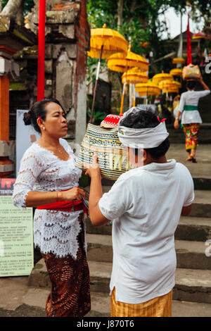 UBUD, INDONESIA - MARCH 2: Child helps his mother during the celebration before Nyepi (Balinese Day of Silence) on March 2, 2016 in Ubud, Indonesia. Stock Photo