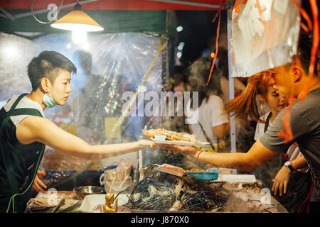 CHIANG MAI, THAILAND - AUGUST 27: Food vendor cooks and sells fish and seafood at the Saturday Night Market (Walking Street) on August 27, 2016 in Chi Stock Photo