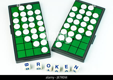 White Broken Heart Othellos on Separated Green Grid Othello Board with Alphabet Blocks say BORKEN Isolated Stock Photo