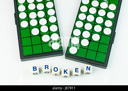 White Broken Heart Othellos on Separated Green Grid Othello Board with Alphabet Blocks say BORKEN Isolated Stock Photo