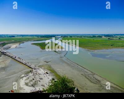 Looking down from Mont Saint-Michel as people swarm back and forth across the bridge over the Couesnon River. Mont Saint-Michel, France. Stock Photo