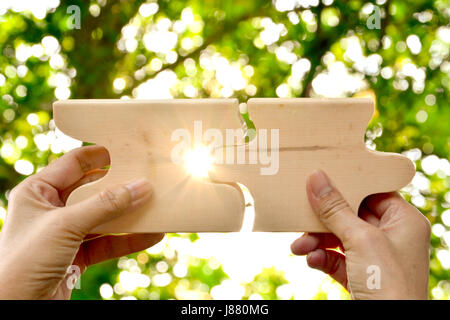 hand holding wood jigsaw piece texture pattern on nature background Stock Photo