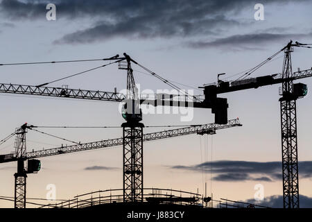View of construction cranes on construction of an apartment house site with silhouetted over amazing abstract sunrise sky Stock Photo