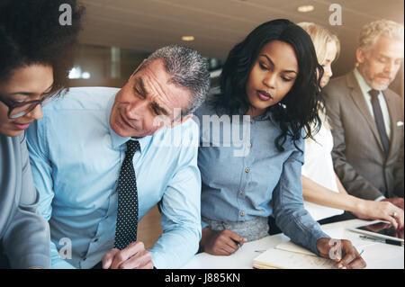 Business men and women working with papers and talking while collaborating in contemporary office. Stock Photo