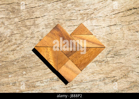 Tangram puzzle in heart shape on wooden background Stock Photo