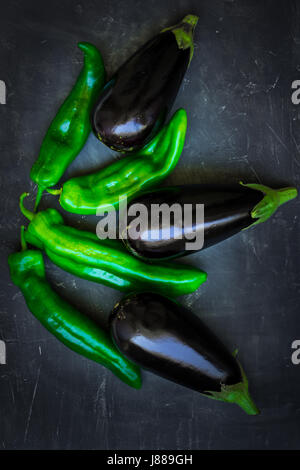 Fresh ripe purple eggplants green italian peppers composition on dark background, healthy eating concept, food ingredients, vegetarian, vegan, minimal Stock Photo