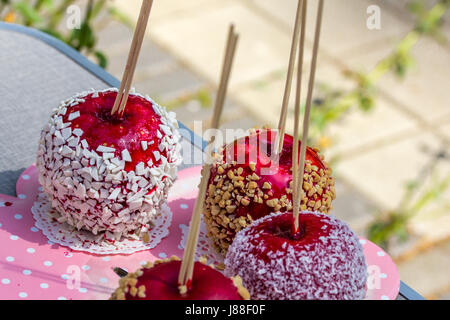 Homemade gourmet caramelized red apples with nuts and chocolate drizzle sitting on large pimk plate. Stock Photo