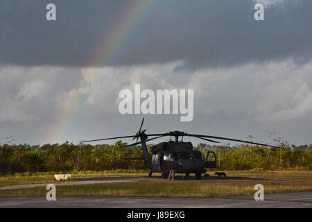 A UH-60 Black Hawk helicopter crewmember with the 1-150th Assault Helicopter Battalion, New Jersey Army National Guard, exits the aircraft at Price Barracks, Belize Defense Force Headquarters, Ladyville, Belize, May 3, 2017. The 1-150th provided aviation support for Beyond the Horizon 2017 - Belize including moving personnel to the work sites, as well as medical evacuation. BTH 2017 is a partnership exercise between the Government of Belize and U.S. Southern Command that will provide three free medical service events and five construction projects throughout the country of Belize from March 25 Stock Photo