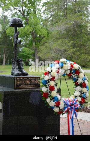 U.S. Service members and community members honor fallen heroes with a wreath at the Bronze Cross Statue Memorial Wreath Laying Ceremony at Joint Base Langley-Eustis, Va., May 20, 2017. The monument depicts the traditional battlefield cross with a soldier’s helmet perched on a rifle, flanked by a pair of combat boots. (U.S. Air Force photo/Airman 1st Class Kaylee Dubois) Stock Photo