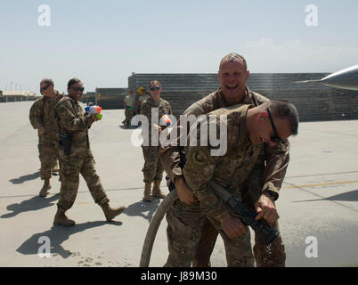 Brig. Gen. Jim Sears, commander of the 455th Air Expeditionary Wing, wrestles a fire hose away from Chief Master Sgt. Peter Speen, command chief of the 455th AEW, after completing his fini flight at Bagram Airfield, Afghanistan, May 22, 2017. Sears, who commanded the 455th AEW for the last 12 months, is a command pilot with more than 3,200 flying hours, including combat missions over Iraq and Afghanistan. (U.S. Air Force photo by Staff Sgt. Benjamin Gonsier) Stock Photo