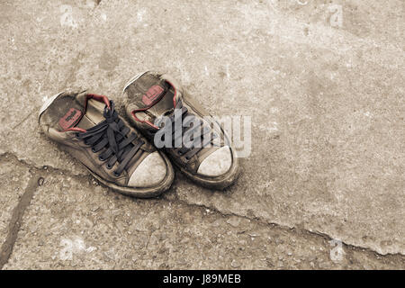 Pair of dirty black sneakers on street background Stock Photo