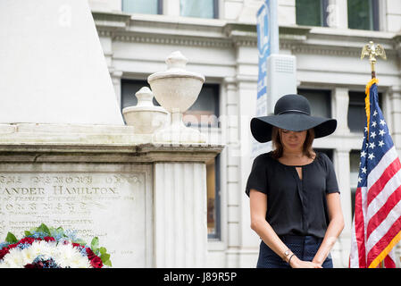 Cast member Lexi Lawson (Eliza Hamilton) of the esteemed Broadway musical, Hamilton bows her head in a moment of silence with the Coast Guard Cutter Hamilton crew, to honor the shared namesake of their play and vessel, founder of the Coast Guard, Alexander Hamilton, at his gravesite at Trinity Church, in New York City, May 26, 2017. The wreath-laying ceremony was a part of Fleet Week New York and Memorial Day weekend activities. U.S. Coast Guard photo by Petty Officer 1st Class LaNola Stone. Stock Photo