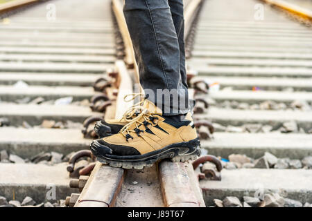 A boy standing on railway tracks wearing leather shoes.