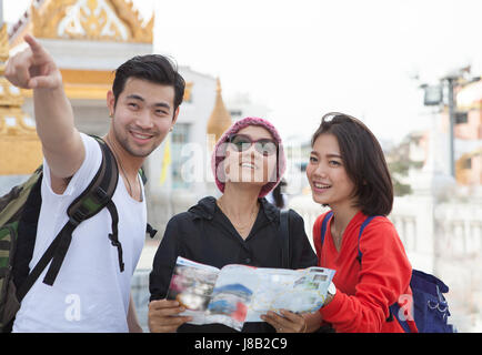 traveling man woman and senior tourist holding travel guide book in hand pointing to destination for visiting Stock Photo