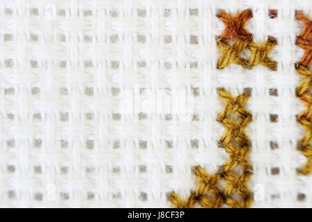 Macro shot fragment embroidery pattern brown thread handmade embroidery, pattern in cross-stitch style on white fabric. Stock Photo