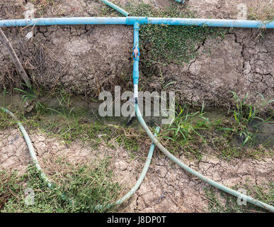 Old PVC pipe with the red plastic valve for used in the countryside farm,Thailand. Stock Photo