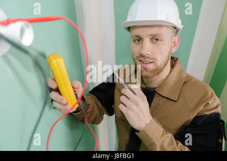 builder using a yellow multimeter to calibrate house Stock Photo