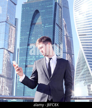 Businessman using smartphone on skyscraper background Stock Photo
