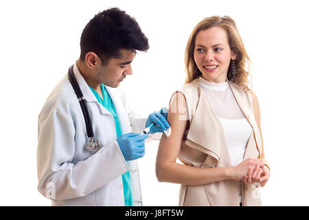 Young handsome doctor with black hair in white gown with stethoscope and blue gloves making an injection of young positive woman with long brown hair  Stock Photo