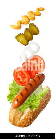 grilled sausage with fresh vegetables falling on bun with sesame seeds. Hot dog with flying ingredients isolated on white background. Ingredients for  Stock Photo