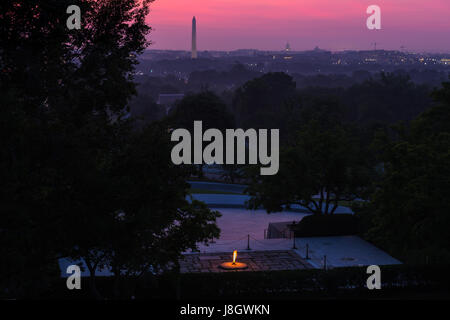 The sky over the Washington, D.C. skyline shows shades of pink and purple prior to sunrise from the John F. Kennedy eternal flame and presidential mem Stock Photo
