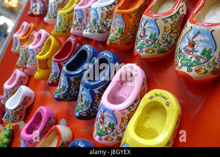 A collection of clogs in various colours with lovely decorations hanging on a wall. Stock Photo