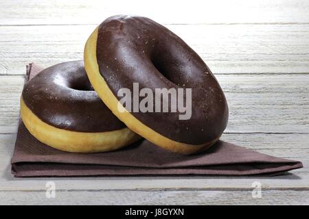 chocolate iced donuts with napkin on wooden background Stock Photo