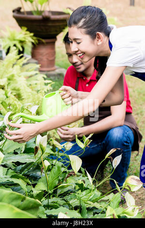 Young woman using a green watering can in the garden Stock Photo