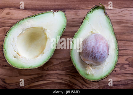 Two halves of a ripe avocado on a wooden background. Stock Photo