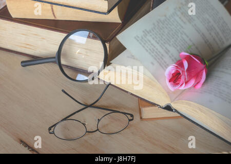 Rose notebook magnifying glasses wood background. Stock Photo