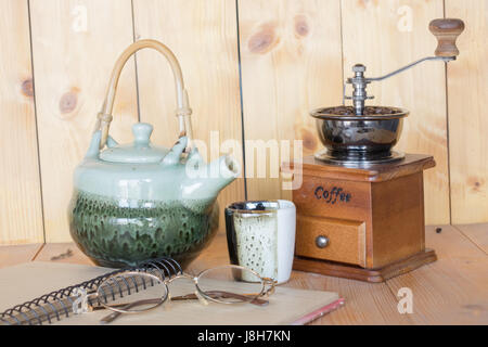 Ground coffee and teapot notebook glasses on a wooden background. Stock Photo