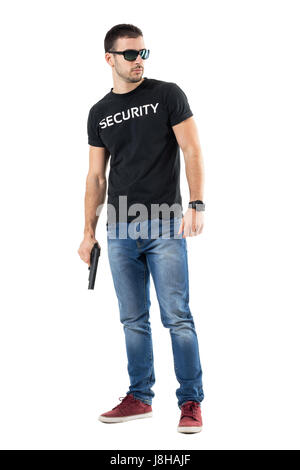 Cautious young undercover cop with sunglasses holding gun looking away. Full body length portrait isolated on white studio background. Stock Photo