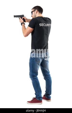 Side rear view of security guard pointing and aiming gun away. Full body length portrait isolated on white studio background. Stock Photo