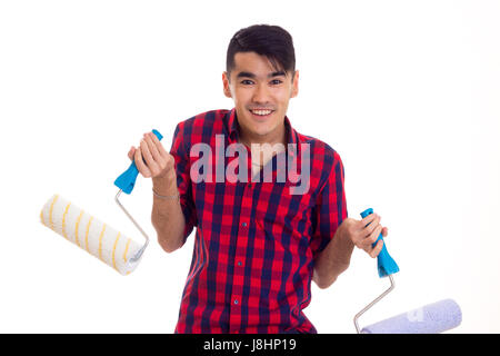 Young optimistic man with dark hair in red plaid shirt holding colored rolls on white background in studio Stock Photo