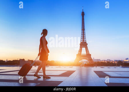 Silhouette of a woman tourist walking with a suitcase on Trocadero in front of Eiffel Tower, Paris, France Stock Photo