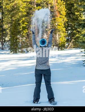 Woman Throws Snow in the Air while wearing snow shoes Stock Photo