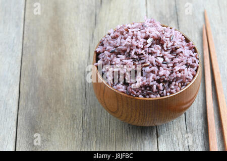 Organic Rice berry in wooden dish on wood background. Stock Photo