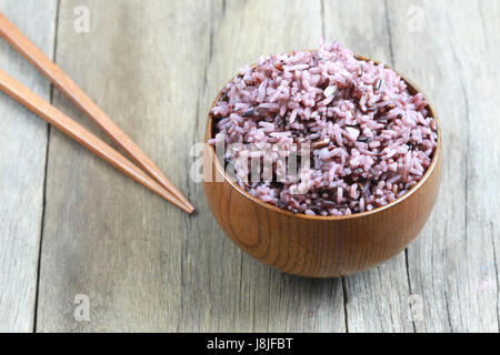 Organic Rice berry in wooden dish on wood background. Stock Photo