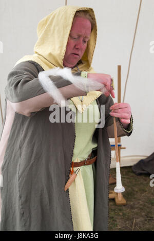 Woman dressed in traditional costume spinning wool in tent at replica of old Viking settlement Stock Photo