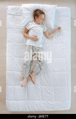 Pleasurable relaxation. Pleasant nice young boy lying on the bed and having a rest while having a nap Stock Photo