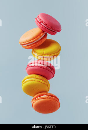 Different types of macaroons in motion falling on light blue background. Sweet and colourful french macaroons falling or flying in motion. Stock Photo