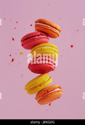 Different types of macaroons in motion falling on pink background. Sweet and colourful french macaroons falling or flying in motion. Stock Photo