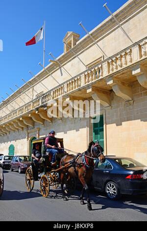 Horse drawn carriage passing the Holy Infirmary along Triq Il-Mediterran, Valletta, Malta, Europe. Stock Photo