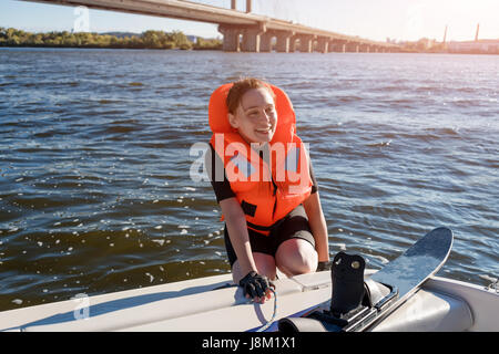 Young fit woman ready to ride water skis siting on the boat closeup. Athlete water skiing and having fun. Living a healthy lifestyle and staying active. Water sports theme Stock Photo