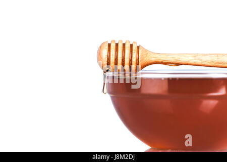 Glass bowl of Honey with wooden drizzler on white background Stock Photo