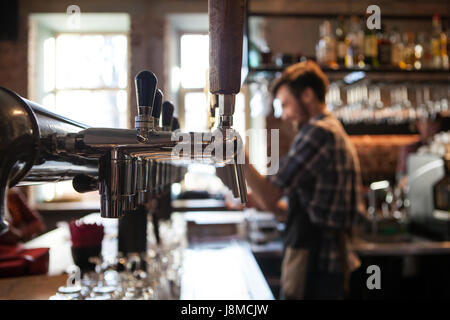 Lot of vintage Golden beer taps in the bar with the bartender in the background Stock Photo