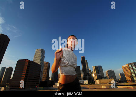 Portrait of young fashion woman posing In elegant dress on rooftop with a view the city of Los Angeles Stock Photo